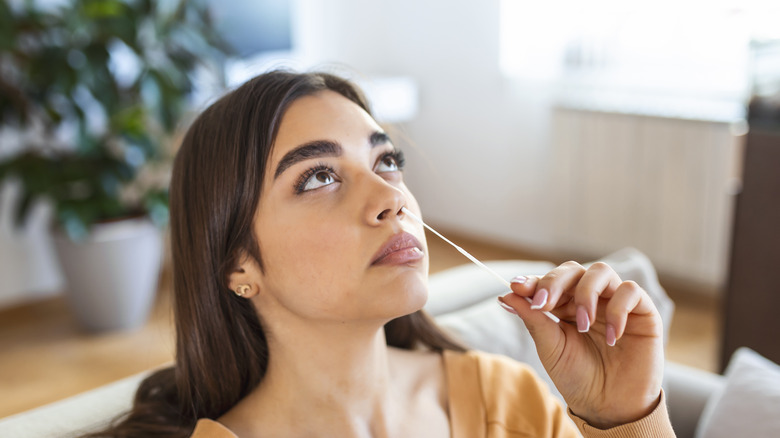 person using cotton swab in nose