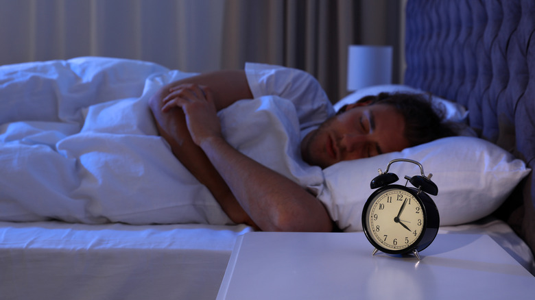 Man sleeping near alarm clock 