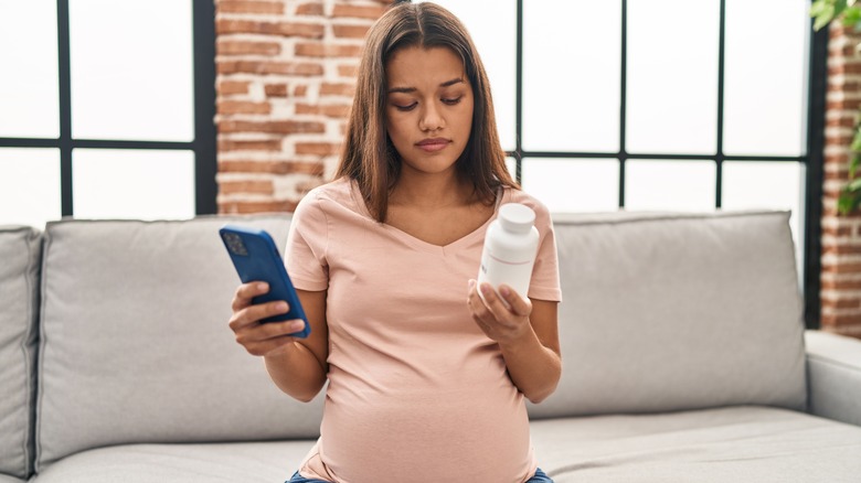 Pregnant person reading pill bottle