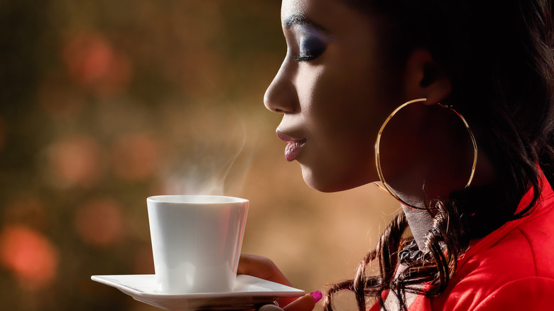 woman smelling a hot cup of tea