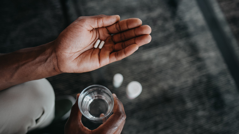 hand holding medication and water