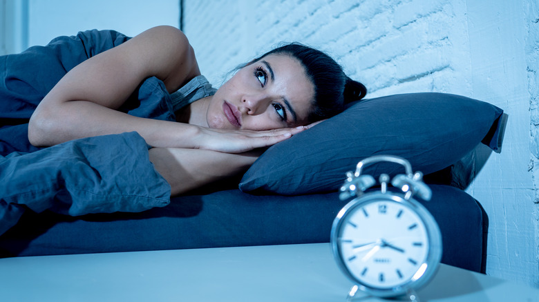 woman at home bedroom lying in bed late at night trying to sleep 