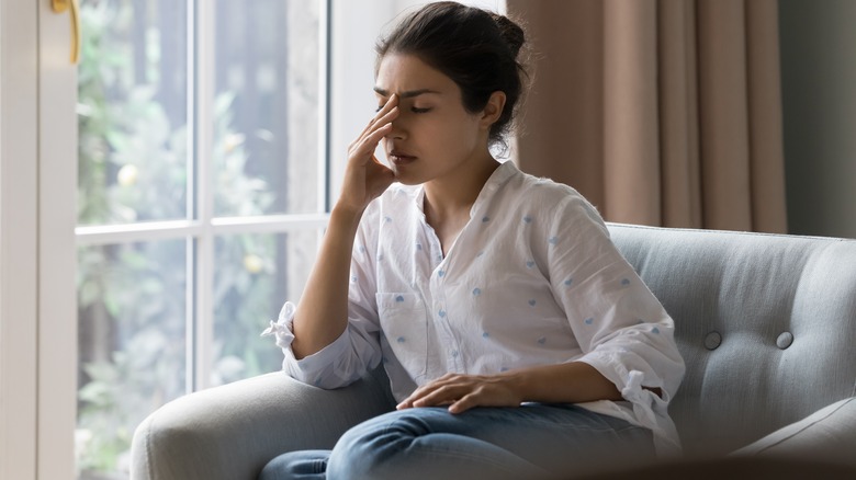 woman sitting on sofa with headache