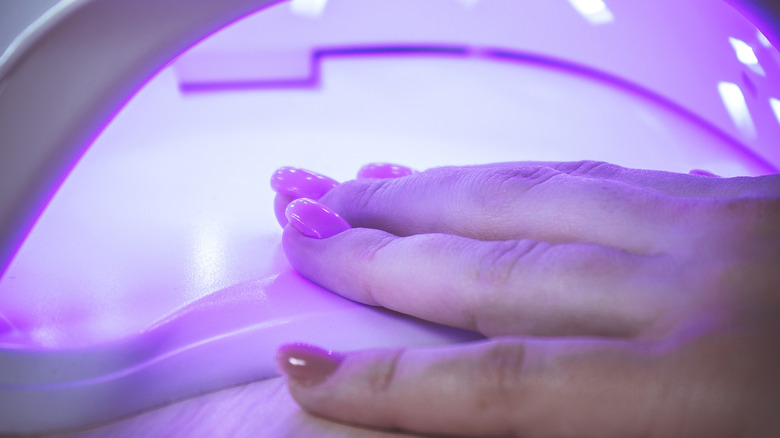 Manicured hand in UV nail dryer