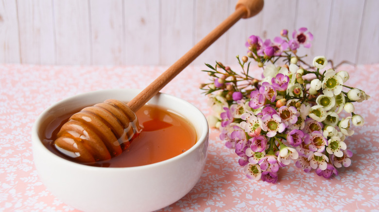 Bowl of honey with white and purple flowers