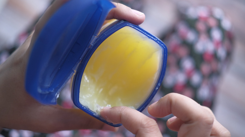 Hand scooping Vaseline out of container