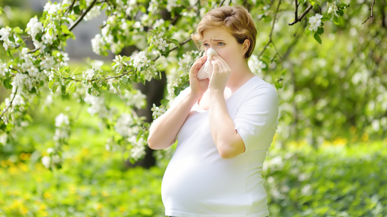 Pregnant woman blowing nose