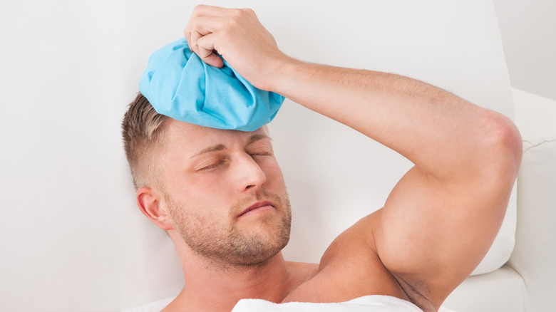 Man nursing a hangover with ice pack