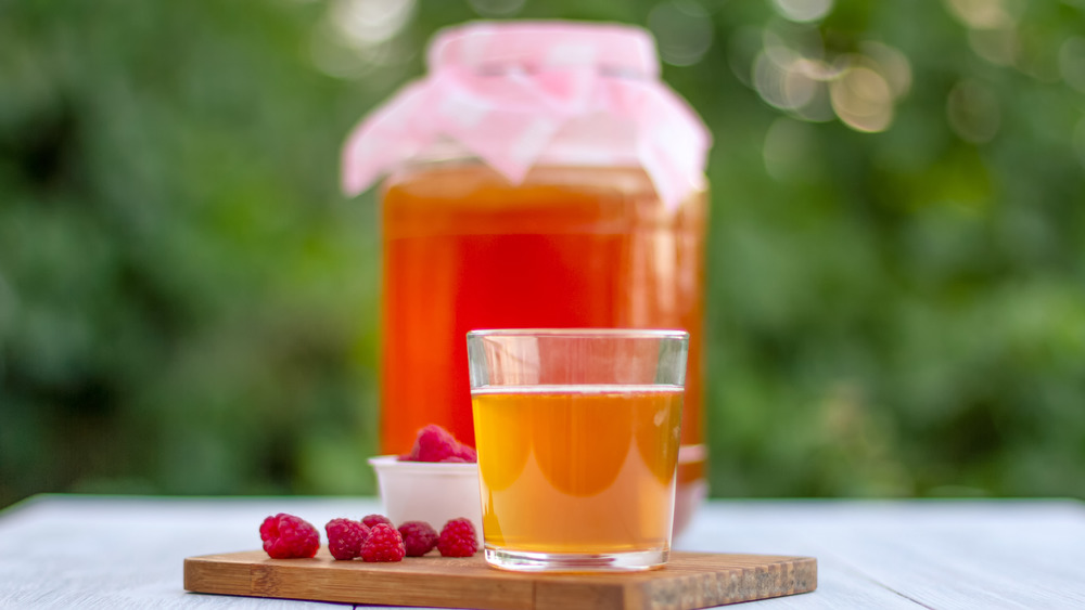 Jar and glass of kombucha with raspberries 