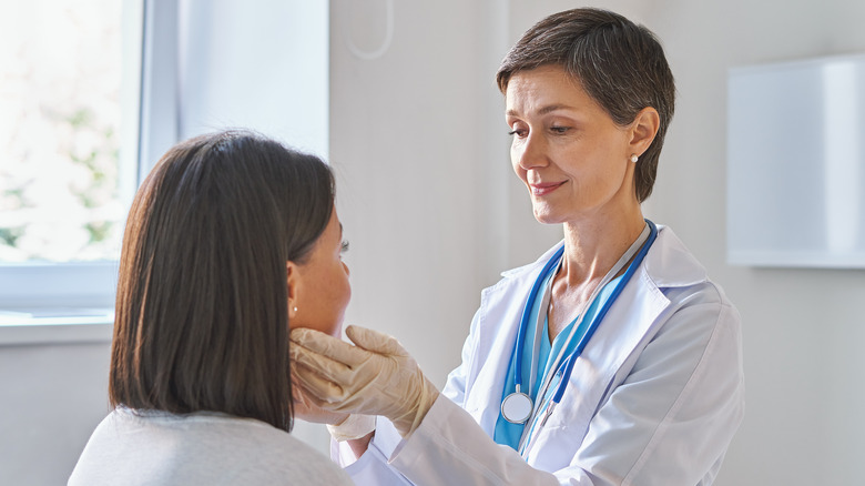 Doctor touching patient's throat