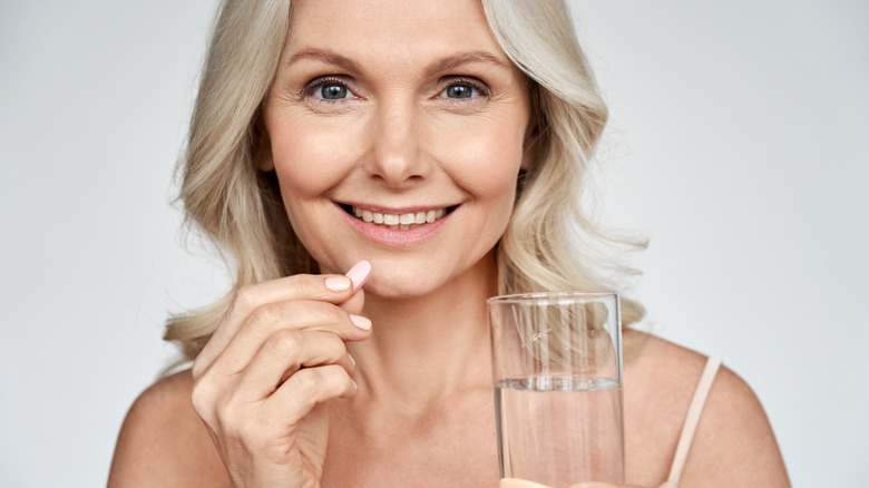 woman taking medication with glass of water