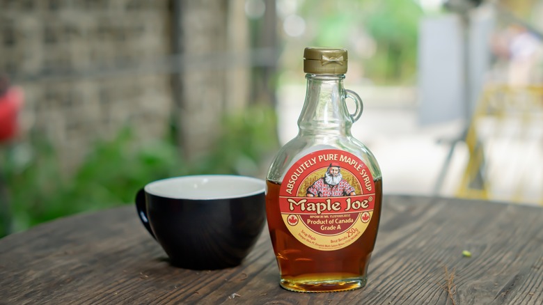 Bottle of maple syrup near cup