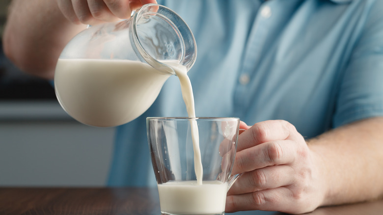 Hand pouring glass of milk