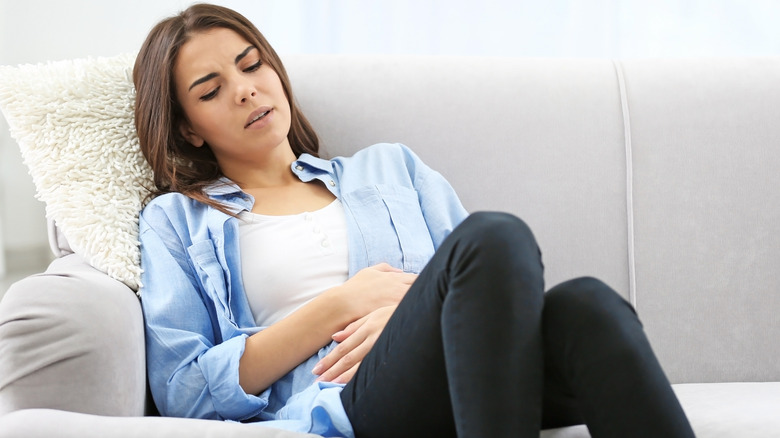 Woman sitting and experiencing abdominal pain