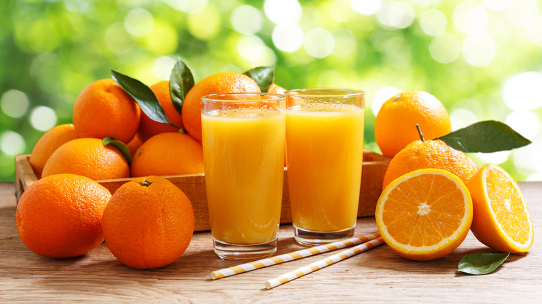 Freshly squeezed orange juice next to whole oranges