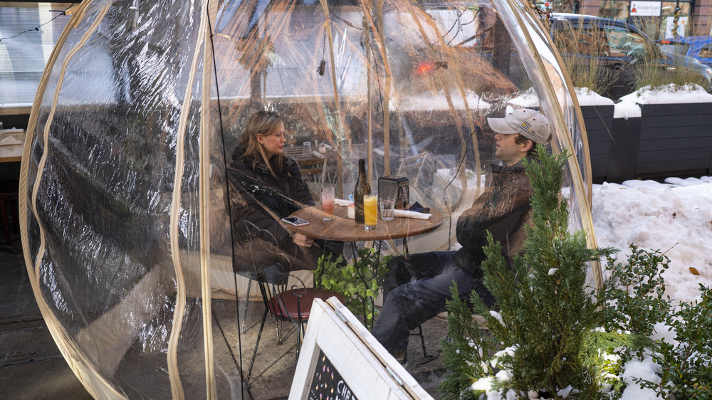 Two people eat in a plastic bubble