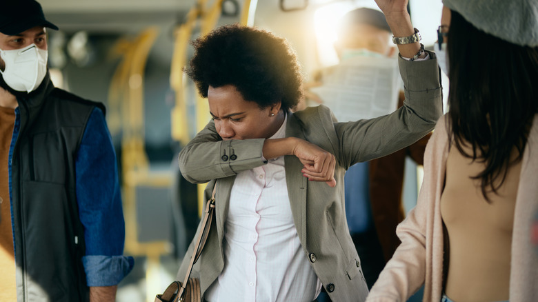 Young woman sneezing on public bus