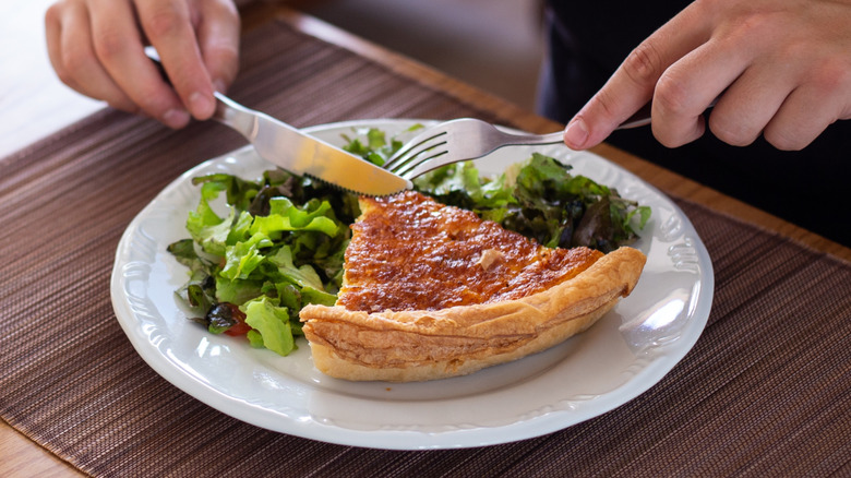 A man eating a slice of quiche