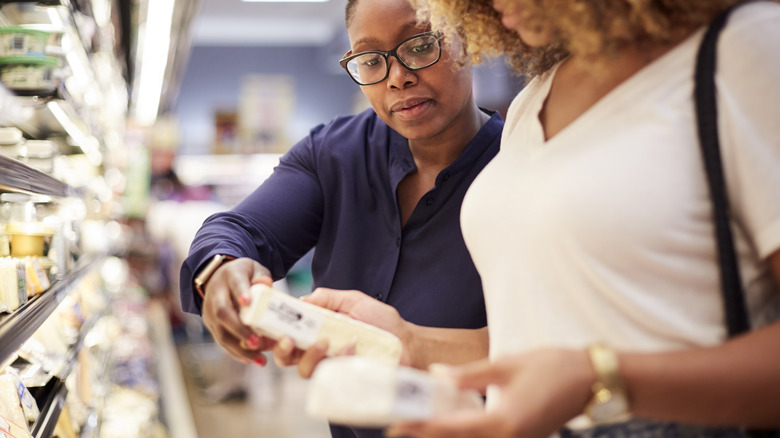 Two women buying cheese at the grocery store