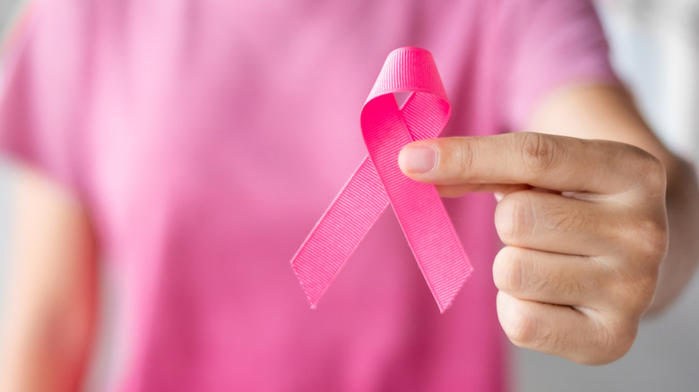 Someone holds a pink breast cancer ribbon