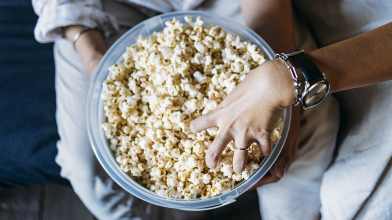 people's hands reaching into a bowl of popcorn