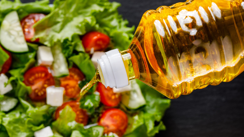 Pouring sunflower oil into a bowl with salad