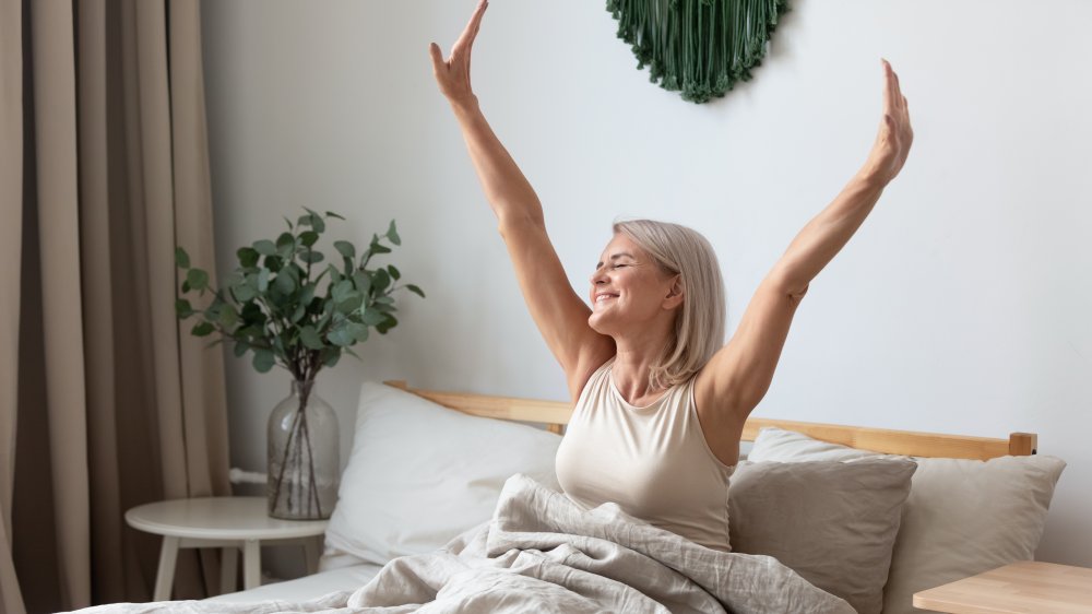 refreshed middle aged woman waking up in bed