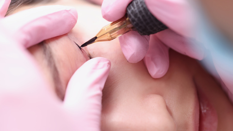 Close up of woman receiving permanent eyelid makeup tattoo