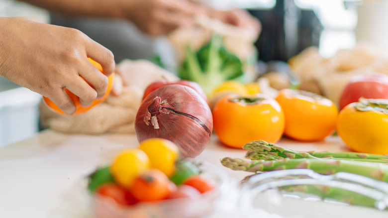 hands preparing assorted fruits and vegetables