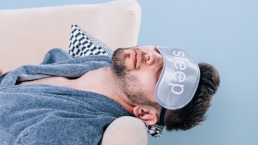  sleeping man in a blue rob wearing an eye mask