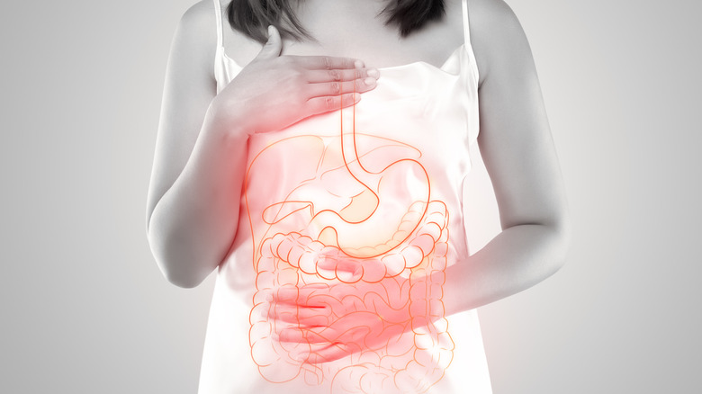 Woman holding body with overlay of digestive tract