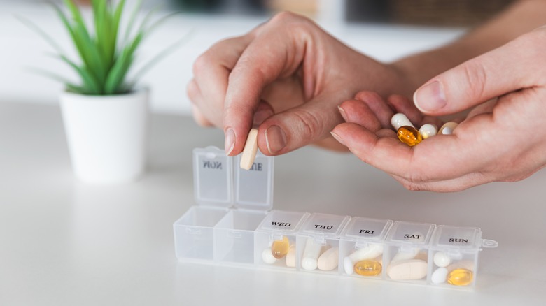 woman's hand placing pills into an organizer