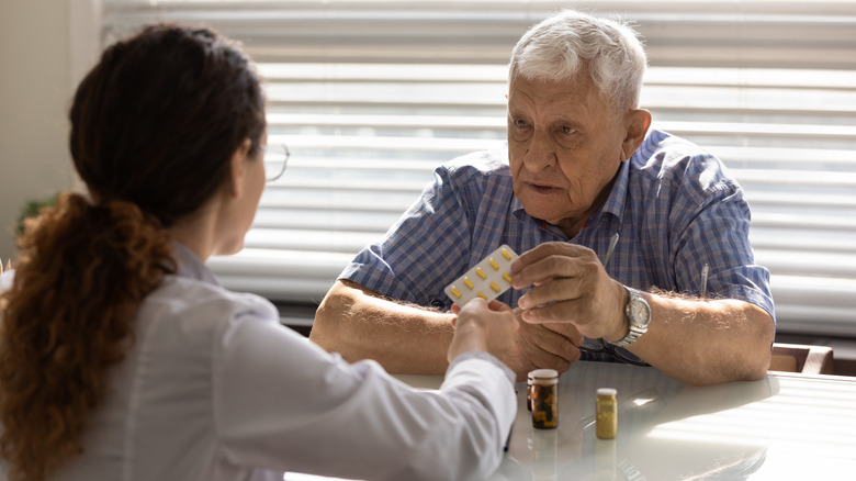 Doctor hands elderly man medication