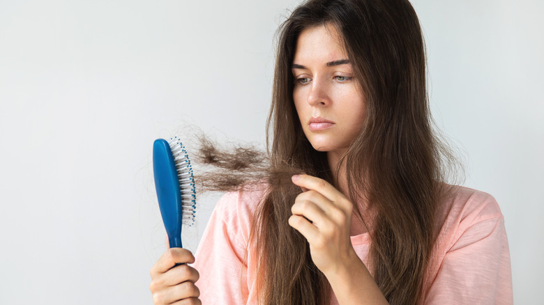 A woman pulls hair out of her hairbrush