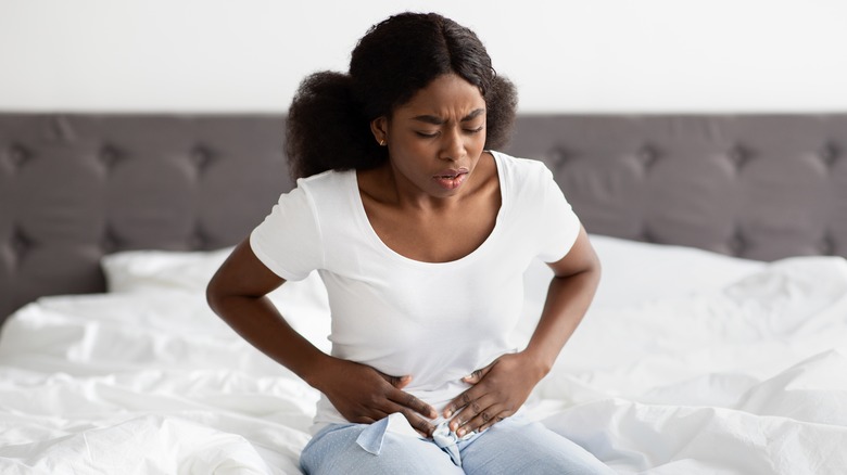 woman holding her gut in pain