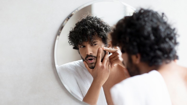 Man looking at acne in mirror