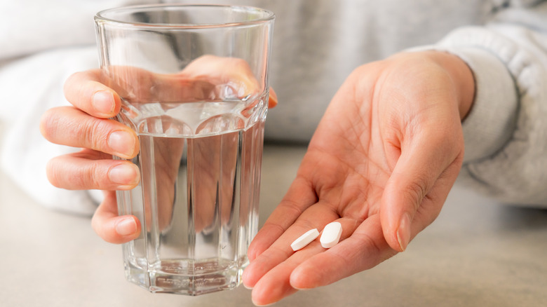 Hands holding glass and medication