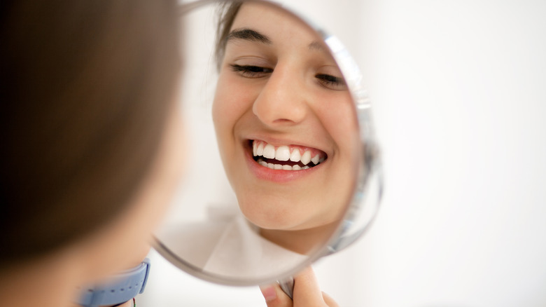 woman looking at her white teeth in the mirror