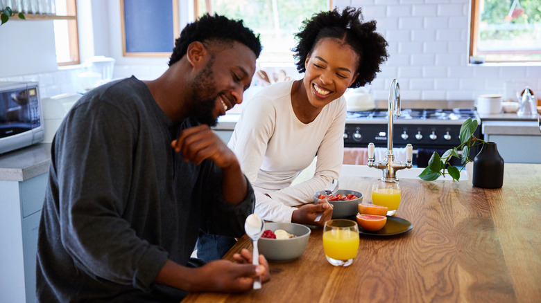 Laughing couple eating breakfast