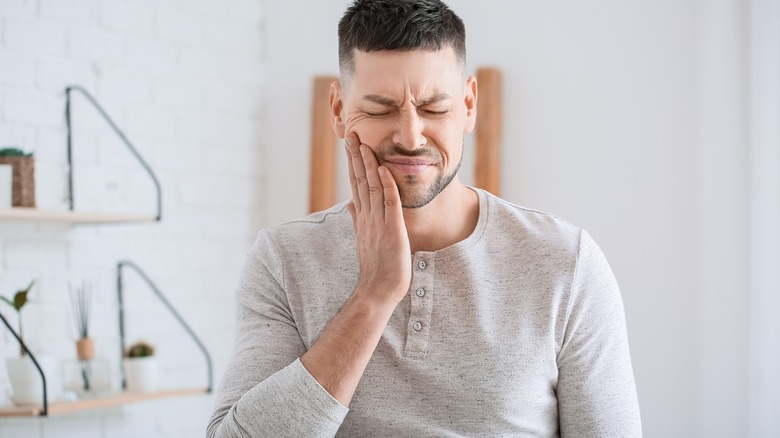 man holding hand on face for toothache