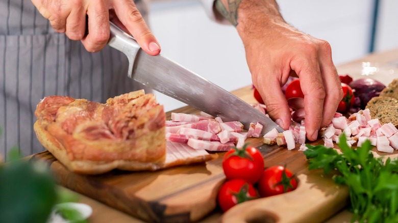 chef dicing bacon on chopping board