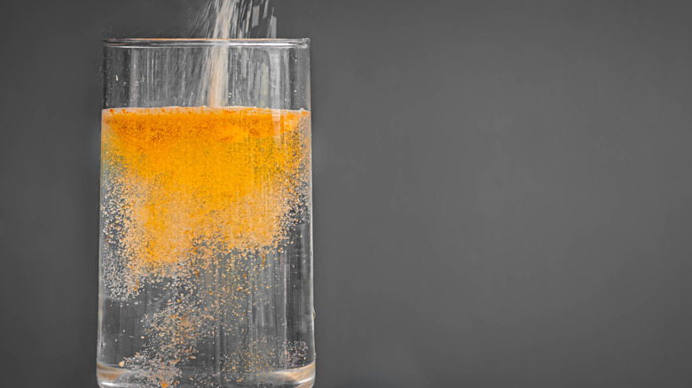 flavoring a glass of water with orange powder 