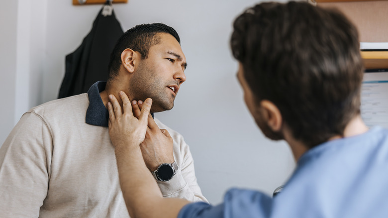 man have his neck checked by a doctor