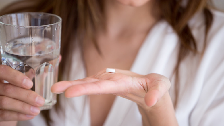 Woman holding glass and pill