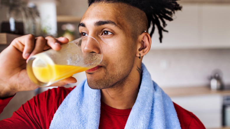 A man drinking a glass of juice after a workout