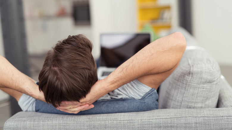 man relaxing on the couch with his pc