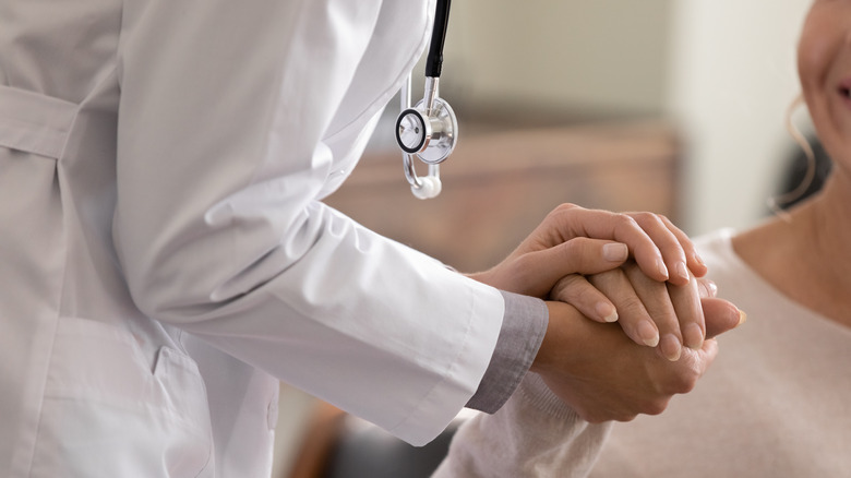A doctor holds the hand of a patient