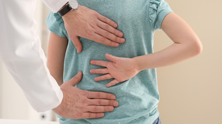 doctor examining child for back pain