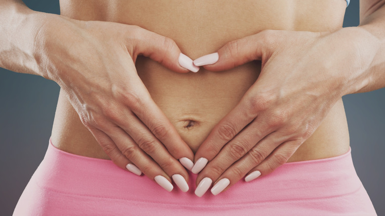 bare female torso with hands making shape of heart