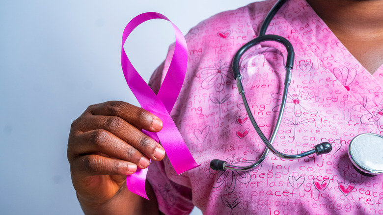 A nurse holds a pink breast cancer ribbon